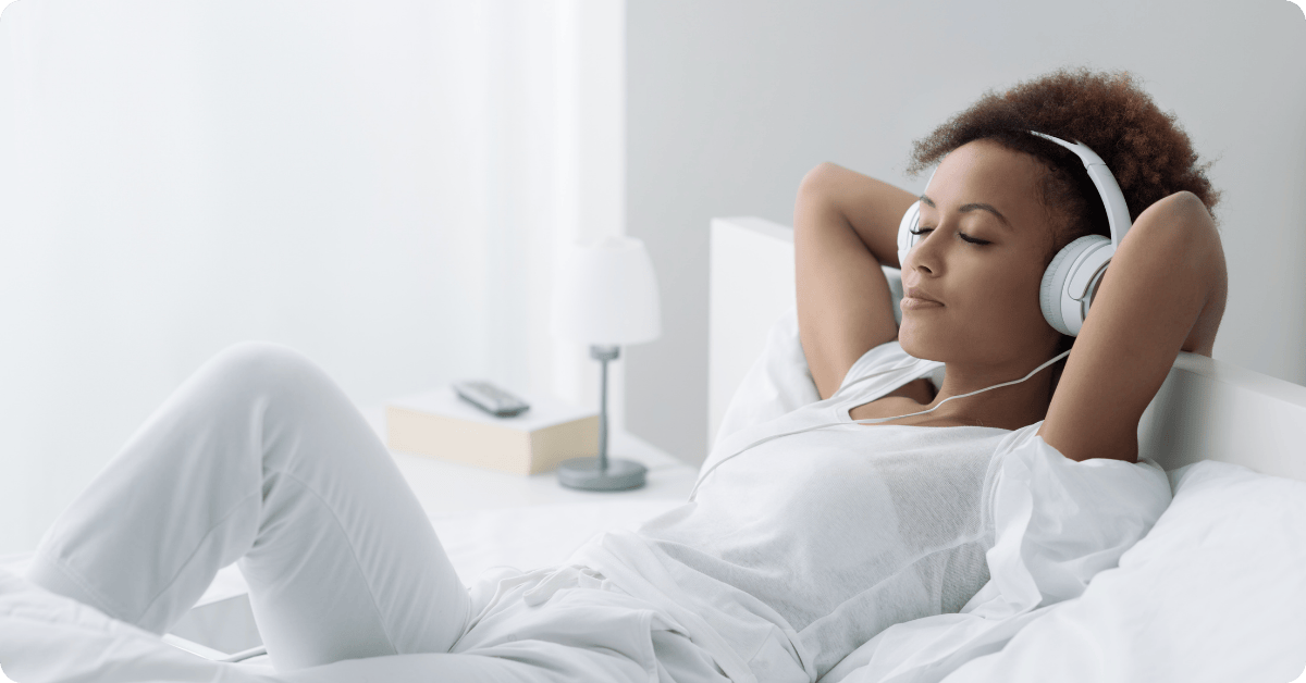 A Woman in Bed Listening to Hypnosis Trance with Headphones